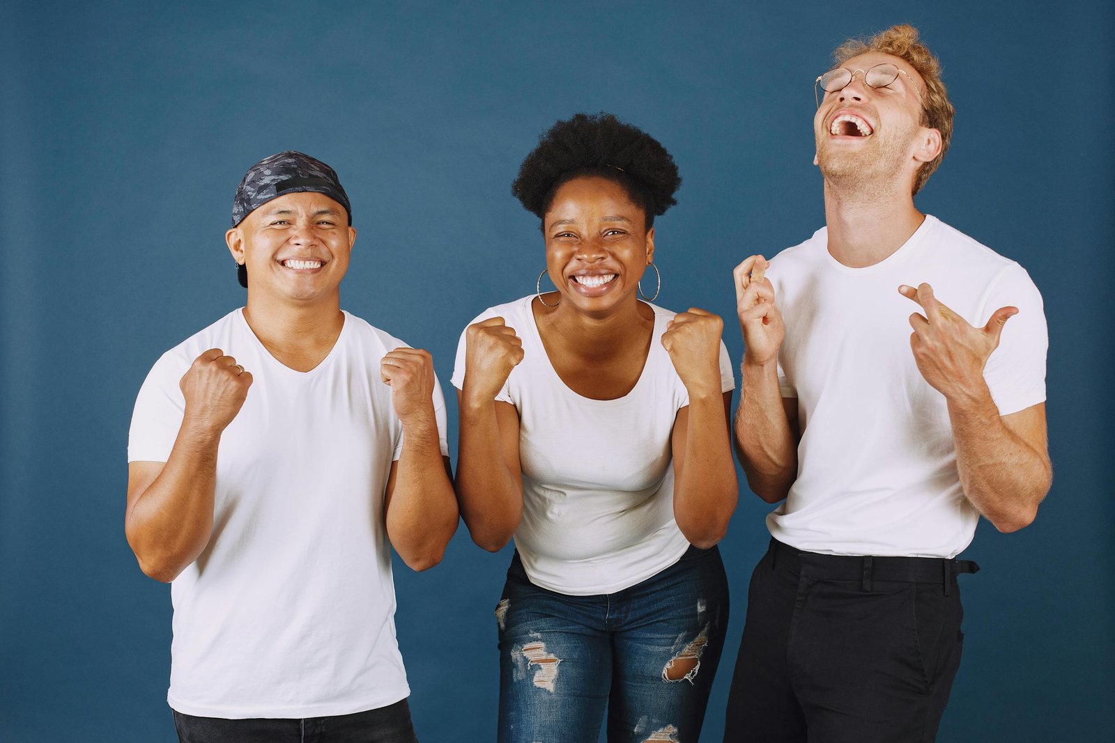 A diverse group of joyful adults celebrating and laughing against a blue studio background.