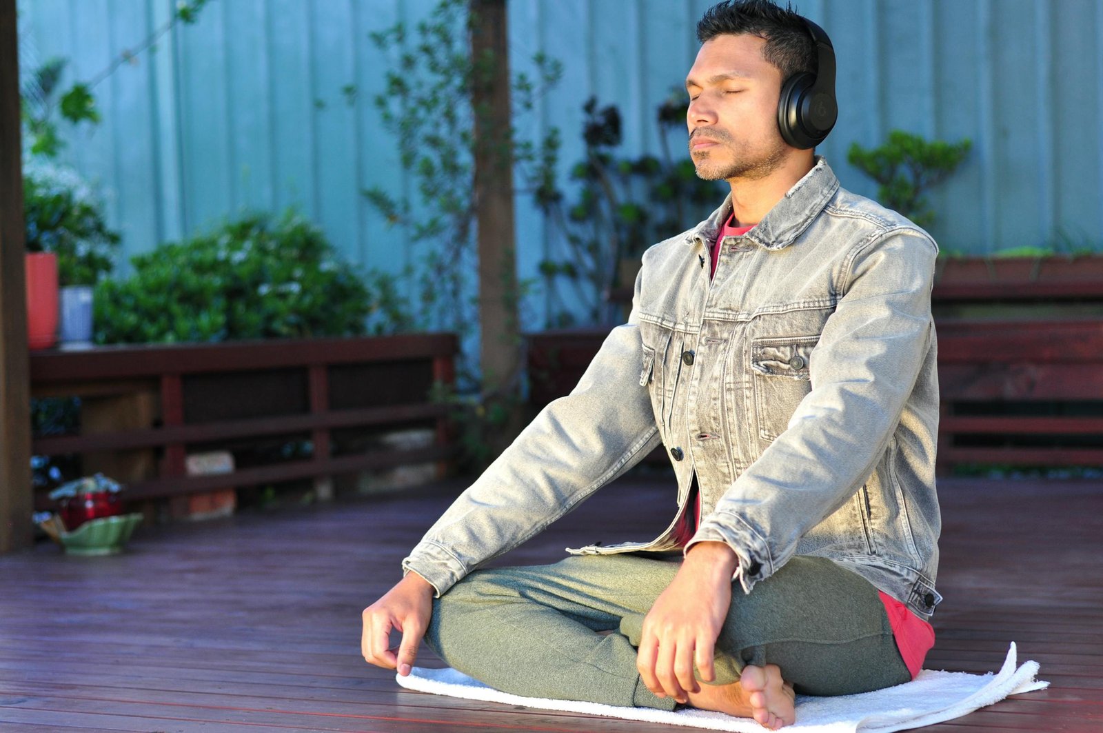 Adult man practicing meditation and relaxation with headphones in a serene outdoor setting.