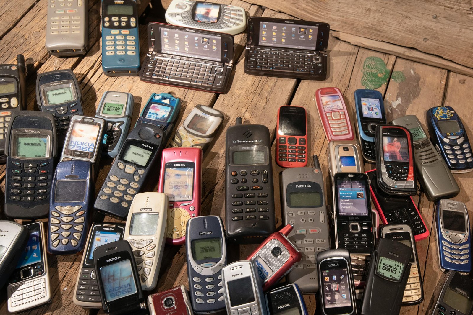An assortment of retro mobile phones displayed on a rustic wooden surface, showcasing nostalgia.