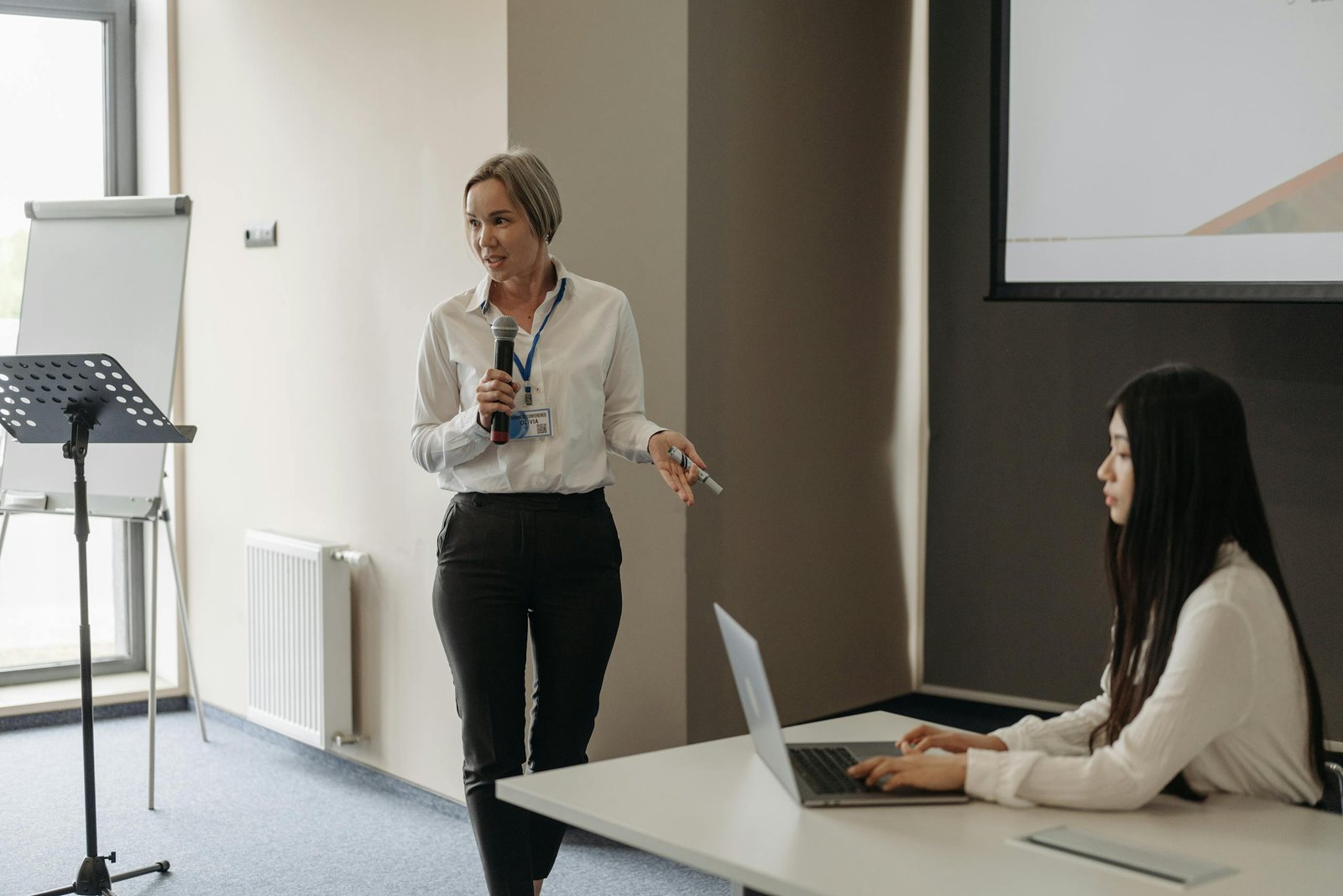 Two women in a business meeting with a presentation and laptop, fostering effective communication.
